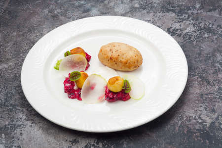 tasty fish cutlet with vegetable side dish on a white plate in a restaurantの写真素材