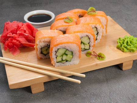 tasty sushi rolls with salmon and cucumber on a wooden boardの写真素材