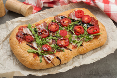 tasty pizza with bacon tomatoes and arugulaの写真素材