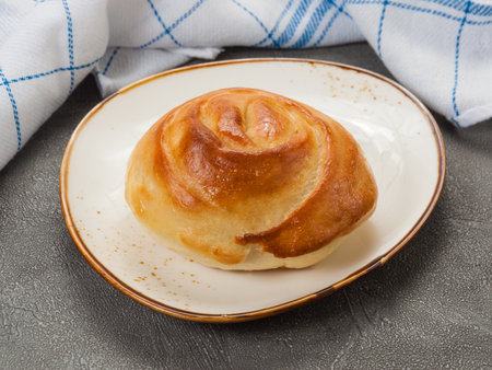tasty homemade bun made of swirled dough on a light plateの写真素材