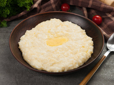 tasty rice porridge with milk and butter in a dark plateの写真素材