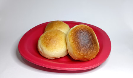 Small round buns on a small red plate with a white background, Photo of the breads with close-up shotsの写真素材