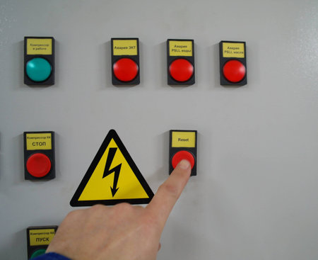 	 On/off buttons and a control led in a black electric box against a white wall near a metal...
