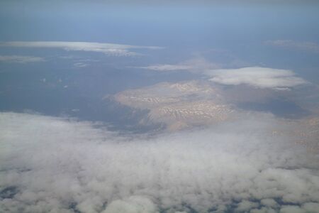 View from the plane window to the clouds and the earthの写真素材