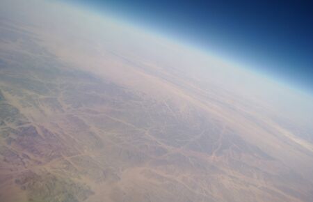 View from the plane window to the clouds and the earthの写真素材