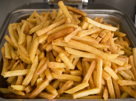 French fries fresh cooked. Restaurant deep fryer, metal container with lots of potatoes fried. Street food, fast food. Potato fries closeup. Roasted tasty potatoesの写真素材