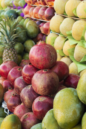 Mango, melon, pineapple and pomegranate are displayed on the farm market. Fruit background. Healthy eating. Concept of autumn agricultural harvest (selective focus)の写真素材
