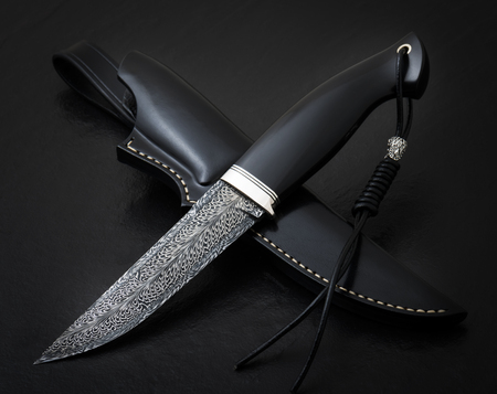 Hunting knife from Damascus mosaic on a black background. Leather Sheath Handmadeの写真素材