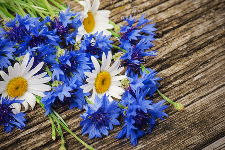 bouquet of blue cornflowers and daisies close-up on a wooden backgroundの写真素材