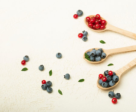 wooden spoons with currants and blueberries on a gray backgroundの写真素材
