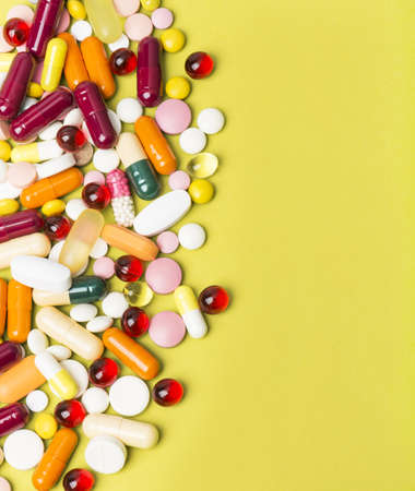 Colorful pills and capsules on yellow backgroundの写真素材