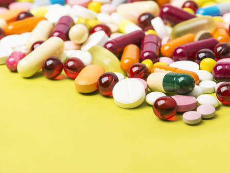Colorful pills and capsules on yellow backgroundの写真素材