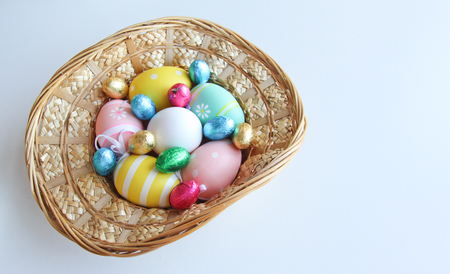 Easter festive frame with eggs in a basket on white wooden table with copyspaceの写真素材