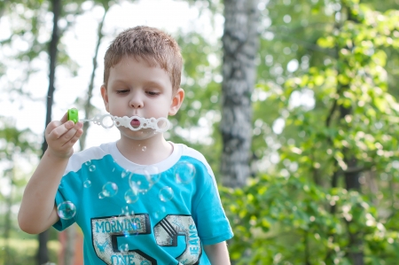 Little boy blowing soap bubbles in summer parkの写真素材