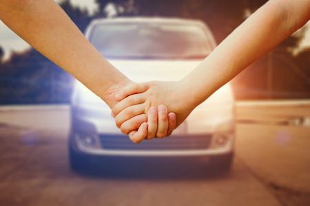 Children holding hands and walking up the road. On the background of the road with a car. Safety movement. Instagram filter.の写真素材