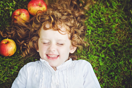 Curly girl lies on the grass and smilingの写真素材