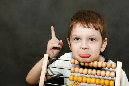Boy in surprise spread his arms near the wooden abacus.の写真素材
