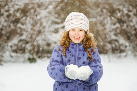 Winter portrait of a little smiling girl, holds in its hands snowing.の写真素材