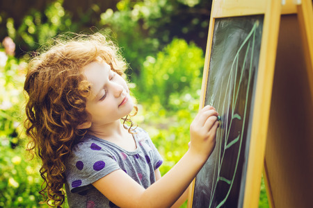 Girl writes in chalk on a blackboard. Education concept. Toning photo.の写真素材