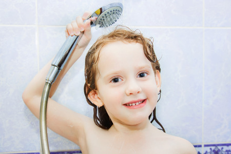 little girl in the bathroom holding a showerの写真素材