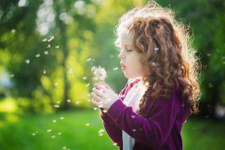 Pretty girl blowing dandelion. の写真素材