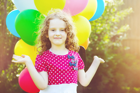 Happy curly girl with colorful balloon in summer park. の写真素材