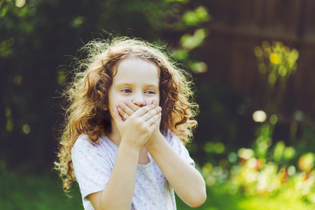 Little girl covering her mouth with her hands. Surprised or scared.の写真素材