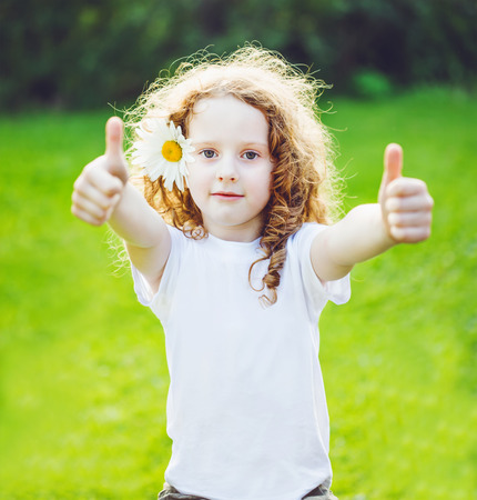 Little girl with whie t-shirt, showing thumbs up.の写真素材