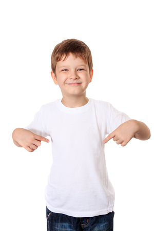 Happy little boy pointing his fingers on a blank t-shirt, a place for your advertising.の写真素材