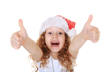 Funny girl in Santa hat showing thumbs up, in light background. Christmas background concept.の写真素材