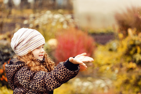 Girl catches in her hands raindrops in autumn park.の写真素材