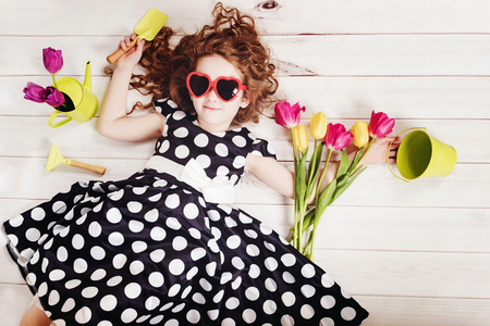 Curly girl with bouquet of tulips lying on white wooden floor. Spring background, Birthday party, Healthy lifestyle, Valentine day concept.の写真素材