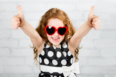 Laughing girl with sunglasses in heart shape, showing thumbs up.の写真素材