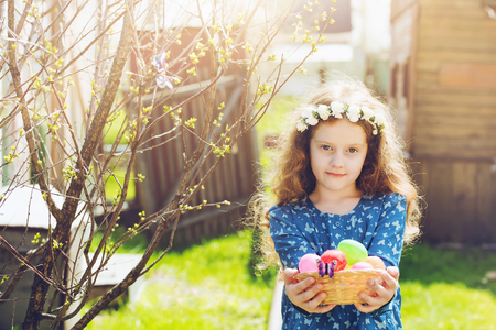 Little girl holding a basket with Easter eggs. Happy easter holiday concept.の写真素材