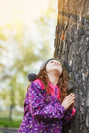 Praying little girl looking up. Happy childhood and world peace concept.の写真素材