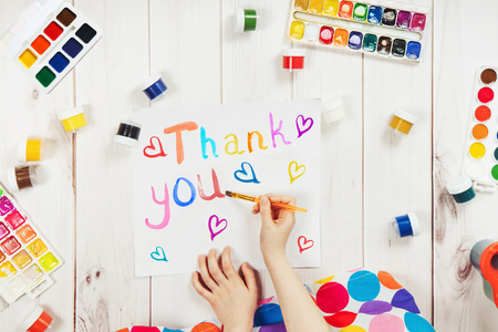 Child hand is writing in album word "Thank you".  Thanksgiving greeting card.の写真素材