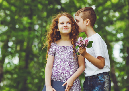 Little boy and girl whispers in spring park.の写真素材