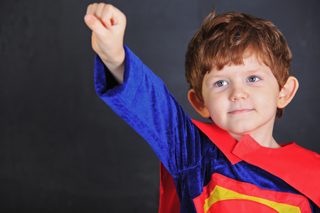 Superhero child in red  cloak, stand near chalkboard.の写真素材