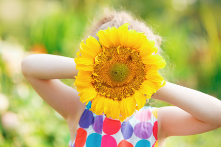 Child with smiling head sunflower. Healthcare, medical and happy childhood concept.の写真素材