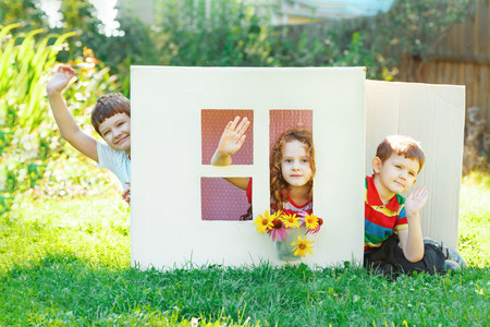 children play in the house made of cardboard box. Little boy and girl dream about new home and family.の写真素材