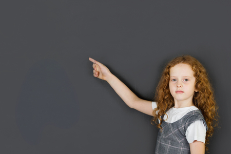Schoolgirl pointing on chalkboard, education conceptの写真素材