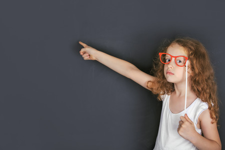 Smart child with red glasses points a finger at lighted lamp. Education and Leadership concept.の写真素材