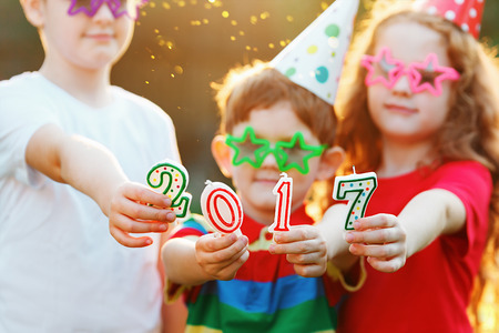 Happy child friend in carnival party hold 2017 candles. Happy childhood, christmas, New Year concept. Focus for hand and candles.の写真素材