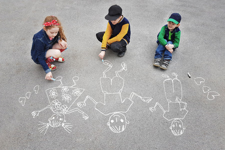 Children is drawing sun on asphalt in spring park.の写真素材