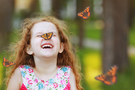 Funny laughing curly girl with a butterfly on his nose. Healthy smile with white teeth. Free breathing concept.の写真素材