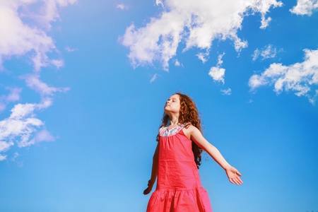 Little girl closed her eyes and breathes the fresh air in the park.の写真素材