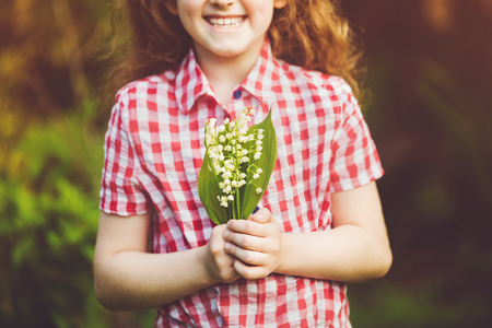 Lily of the valley in child hand. Mum, Dad's Day concept. Toning for instagram filter.の写真素材