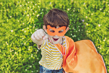 Laughing superhero child in summer park.の写真素材