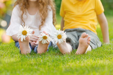 Little girl and boy with barefoot in summer park. Health, medical, happy childhood concept.の写真素材