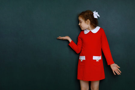 Smart curly girl show on blackboard in classroom. Education, holiday concept.の写真素材
